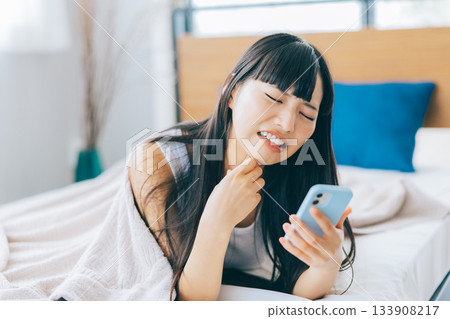 A woman feeling negative while looking at her smartphone in bed 133908217