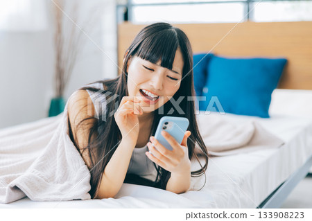 A woman feeling negative while looking at her smartphone in bed 133908223