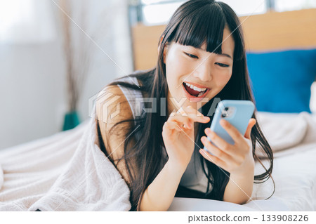 Young woman looking at smartphone in bed Young woman looking at smartphone in bed 133908226