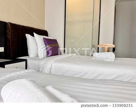 There is a double bed in the hotel room with neatly made bed linen and towels There is a double bed in the hotel room with neatly made bed linen and towels 133908231