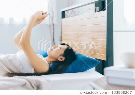 Young woman looking at smartphone in bed 133908267