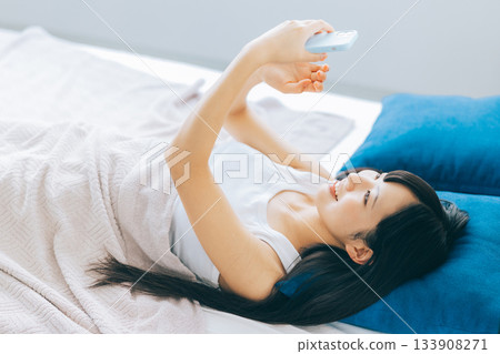 Young woman looking at smartphone in bed 133908271