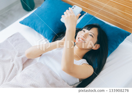 少婦在床上的看智能手機 133908276