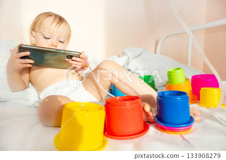 child in hospital lying in bed with mobile phone smiling child in hospital lying in bed with mobile phone smiling 133908279