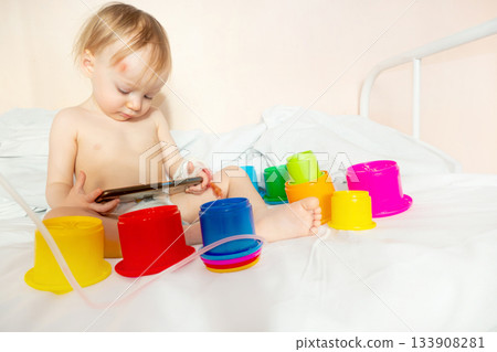 child in hospital lying in bed with mobile phone smiling child in hospital lying in bed with mobile phone smiling 133908281