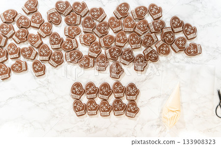 A close-up of beautifully decorated mitten-shaped gingerbread cookies, iced with intricate white royal icing patterns, creating a festive display. 133908323