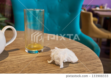 Empty glass and crumpled napkin sitting on wooden table after meal 133908333
