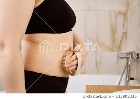 Woman performing dry brushing massage on her side for self-care 133908336