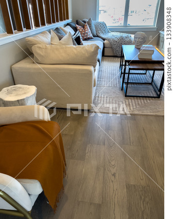 A modern living room featuring two cream-colored sofas and a black-framed coffee table on a light area rug. The neutral palette and natural light create a calm, inviting space. 133908348