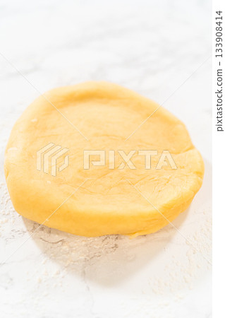 A close-up of sugar cookie dough shaped into a neat disk, ready to be rolled. 133908414