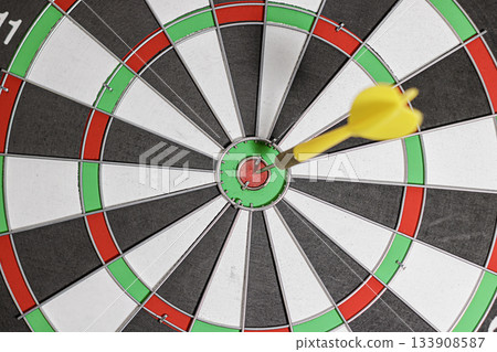 Yellow Dart arrow hitting in the target of classic dartboard. Selective focus. the concept of focus and precision. goals and target. High quality photo Yellow Dart arrow hitting in the target of classic dartboard. Selective focus. the concept of focus and precision. goals and target. High quality photo 133908587