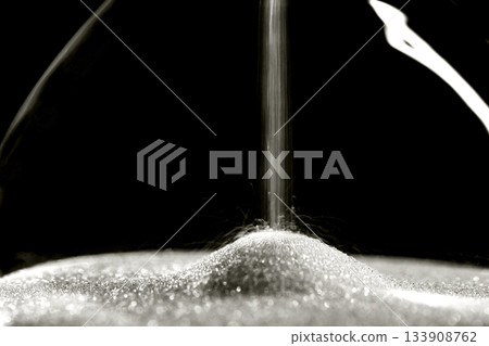 Sparkly hourglass sand on black background. Minimalist low key photo for concepts of time, travel to the desert color of 2026 year cloud white Sparkly hourglass sand on black background. Minimalist low key photo for concepts of time, travel to the desert color of 2026 year cloud white 133908762