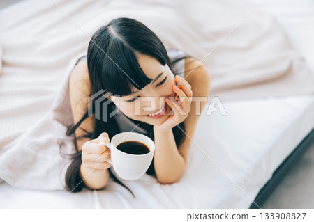 Woman drinking coffee in bed Woman drinking coffee in bed 133908827