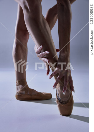 Ballet dancer stretching ankle on pointe with focused emotional tension Ballet dancer stretching ankle on pointe with focused emotional tension 133908988