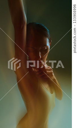 Emotional dancer portrait with raised arm and soft glowing motion in warm tones Emotional dancer portrait with raised arm and soft glowing motion in warm tones 133908996