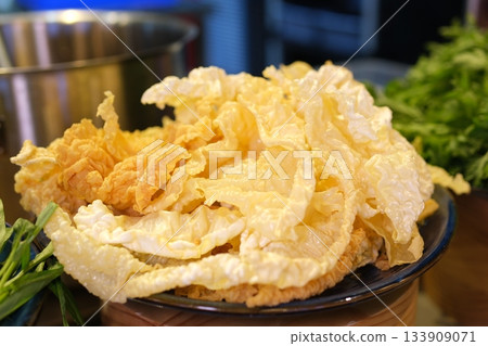 Golden fried tofu blisters with chopsticks showing hollow interior texture, delicious crispy bean curd dish perfect for Asian cuisine and cooking photography. Golden fried tofu blisters with chopsticks showing hollow interior texture, delicious crispy bean curd dish perfect for Asian cuisine and cooking photography. 133909071