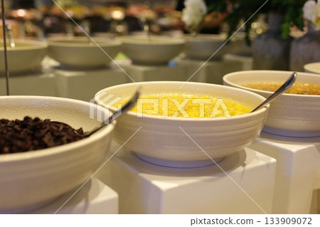 Displaying seven colorful cereal bowls clustered on wooden table, showing milk jar and icons. Flatlay, breakfast, assortment, bowl, grains, kitchen, cozy 133909072