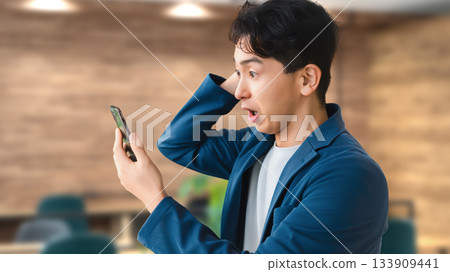 A male businessman surprised at his smartphone A male businessman surprised at his smartphone 133909441
