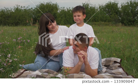 father mother with child kid son sunset, cheerful parent child relaxing green summer meadow, smile face, woman man smile son, people having fun outdoors, husband wife with son on green meadow flowers 133909847
