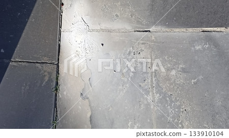 Close-up of a weathered stone pavement texture, highlighting cracks and imperfections. Perfect for architectural visualization, urban planning, and realistic backgrounds. 133910104
