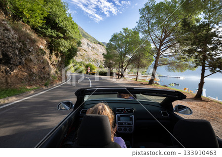 Young woman driving convertible along scenic ocean coast and mountain road at sunset, carefree summer vacation, travel freedom and adventure on coastal highway Young woman driving convertible along scenic ocean coast and mountain road at sunset, carefree summer vacation, travel freedom and adventure on coastal highway 133910463
