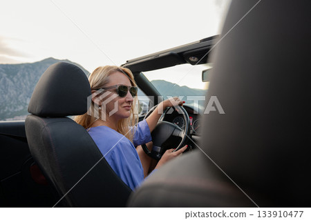 Young woman driving convertible along scenic ocean coast and mountain road at sunset, carefree summer vacation, travel freedom and adventure on coastal highway Young woman driving convertible along scenic ocean coast and mountain road at sunset, carefree summer vacation, travel freedom and adventure on coastal highway 133910477