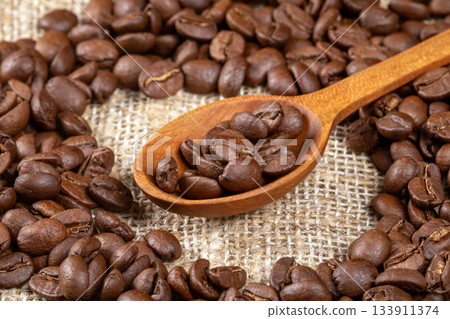 Artistic close-up of coffee beans in a wooden spoon on rustic table 133911374