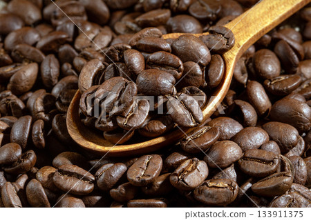 Close-up shot of a wooden spoon filled with fresh coffee beans 133911375