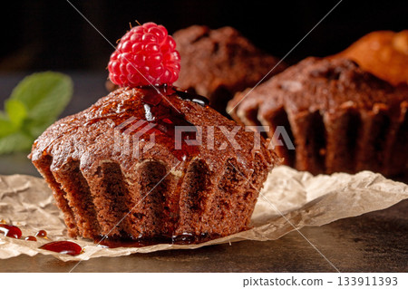 Yummy muffins and fresh raspberries delightfully arranged on a black kitchen table 133911393