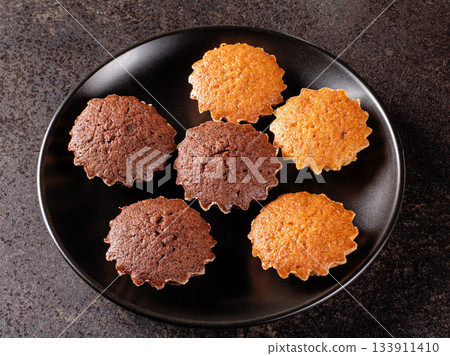 Top view of delicious lemon and chocolate mini muffins on a black plate 133911410