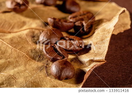 Close-up shot of coffee beans on a rustic dry almond leaf background Close-up shot of coffee beans on a rustic dry almond leaf background 133911416