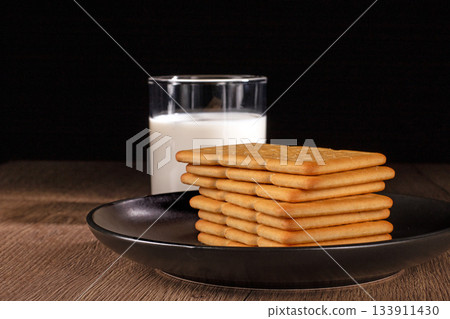 A glass of fresh milk and salty crackers enjoyed on a cozy kitchen table A glass of fresh milk and salty crackers enjoyed on a cozy kitchen table 133911430
