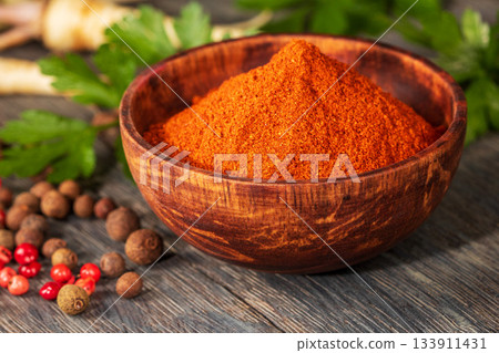 Artistic close-up of red ground pepper in a handcrafted wooden bowl Artistic close-up of red ground pepper in a handcrafted wooden bowl 133911431