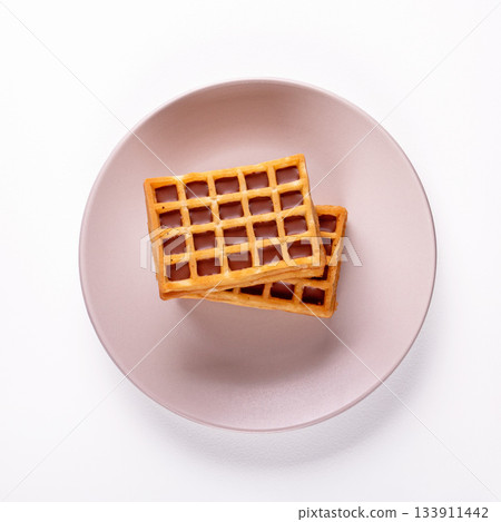 Delicious soft belgian waffles on cream ceramic plate, captured from top view Delicious soft belgian waffles on cream ceramic plate, captured from top view 133911442