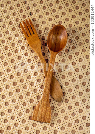 Top view of vintage wooden fork and spoon on rattan napkin background Top view of vintage wooden fork and spoon on rattan napkin background 133911444