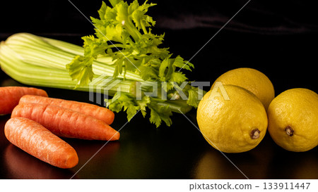 Vibrant lemons, carrots, and celery arranged on rich black background 133911447