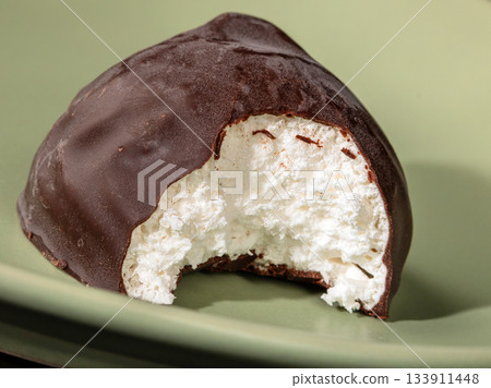 Close-up of bite-sized chocolate marshmallow on a green plate 133911448