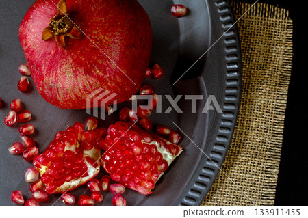 Whole and sliced pomegranate on a vintage metal plate viewed from above Whole and sliced pomegranate on a vintage metal plate viewed from above 133911455