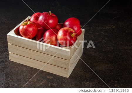Bountiful ripe red apples in a wooden box on a stylish black table 133911553