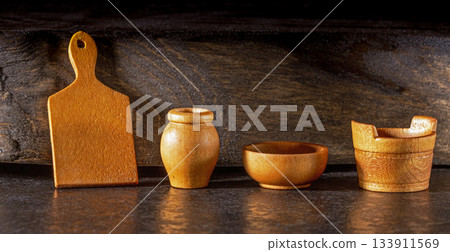 Vintage wooden miniature tableware set displayed on a dark background Vintage wooden miniature tableware set displayed on a dark background 133911569