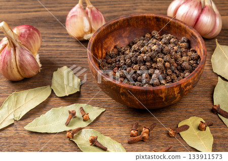 Flavor essentials: an artistic display of bay leaf, garlic, pepper, and cloves on table Flavor essentials: an artistic display of bay leaf, garlic, pepper, and cloves on table 133911573