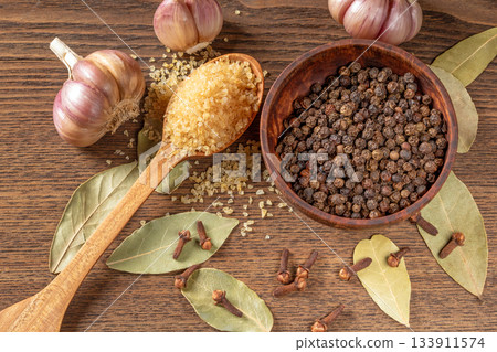 Kitchen table spices: bay leaf, garlic cloves, pepper, and whole cloves in natural light 133911574