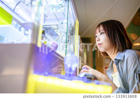 一位年輕女子在渡輪上玩抓娃娃機。 一位年輕女子在渡輪上玩抓娃娃機。 133911608