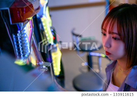 一位年輕女子在渡輪上的遊戲中心玩老虎機。 一位年輕女子在渡輪上的遊戲中心玩老虎機。 133911615