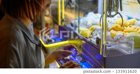 Profile of a woman engrossed in a crane game Profile of a woman engrossed in a crane game 133911620