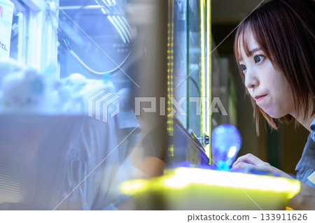 A woman is engrossed in a crane game at a game center on a ferry. A woman is engrossed in a crane game at a game center on a ferry. 133911626