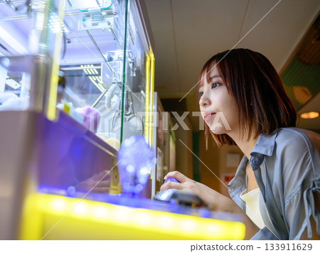 A young woman absorbed in a crane game 133911629
