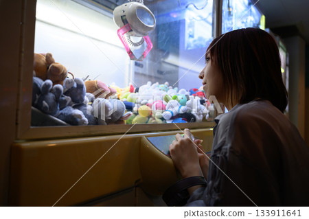 Profile of a woman playing a crane game at a game center on a ferry 133911641