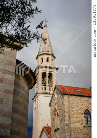 Close-up view of a historic church tower facade in the Old Town of Budva, Montenegro. Focus on stone textures, medieval architecture, and architectural details. Perfect for travel, heritage, European Close-up view of a historic church tower facade in the Old Town of Budva, Montenegro. Focus on stone textures, medieval architecture, and architectural details. Perfect for travel, heritage, European 133911778