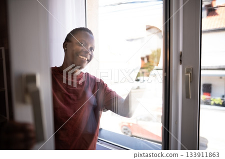 Young Man Cleaning Windows at Home Smiling at Camera Young Man Cleaning Windows at Home Smiling at Camera 133911863